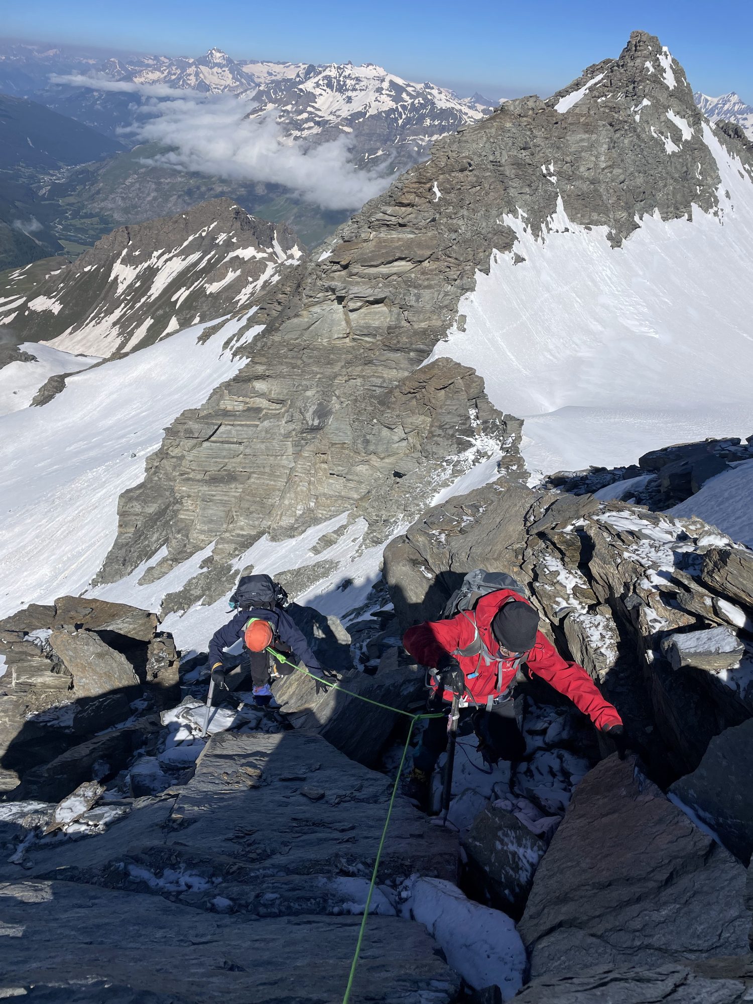 Cordée sur arête rocheuse, sommets et glaciers en arrière-plan