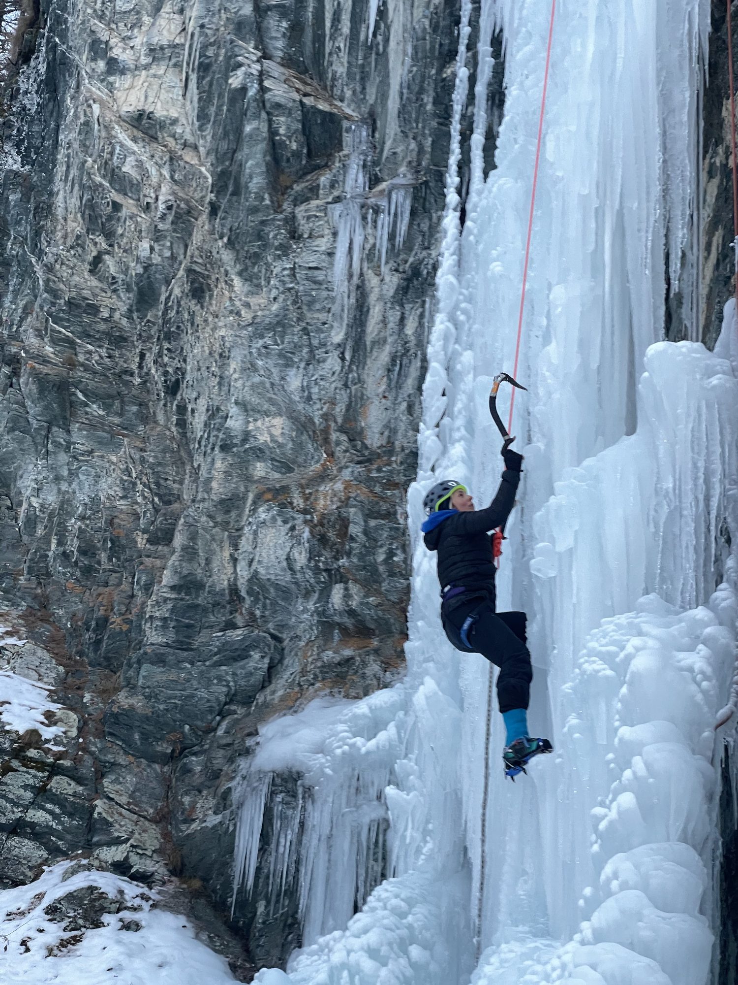 Grimpeuse en tête sur une cascade encaissée, falaise de granit