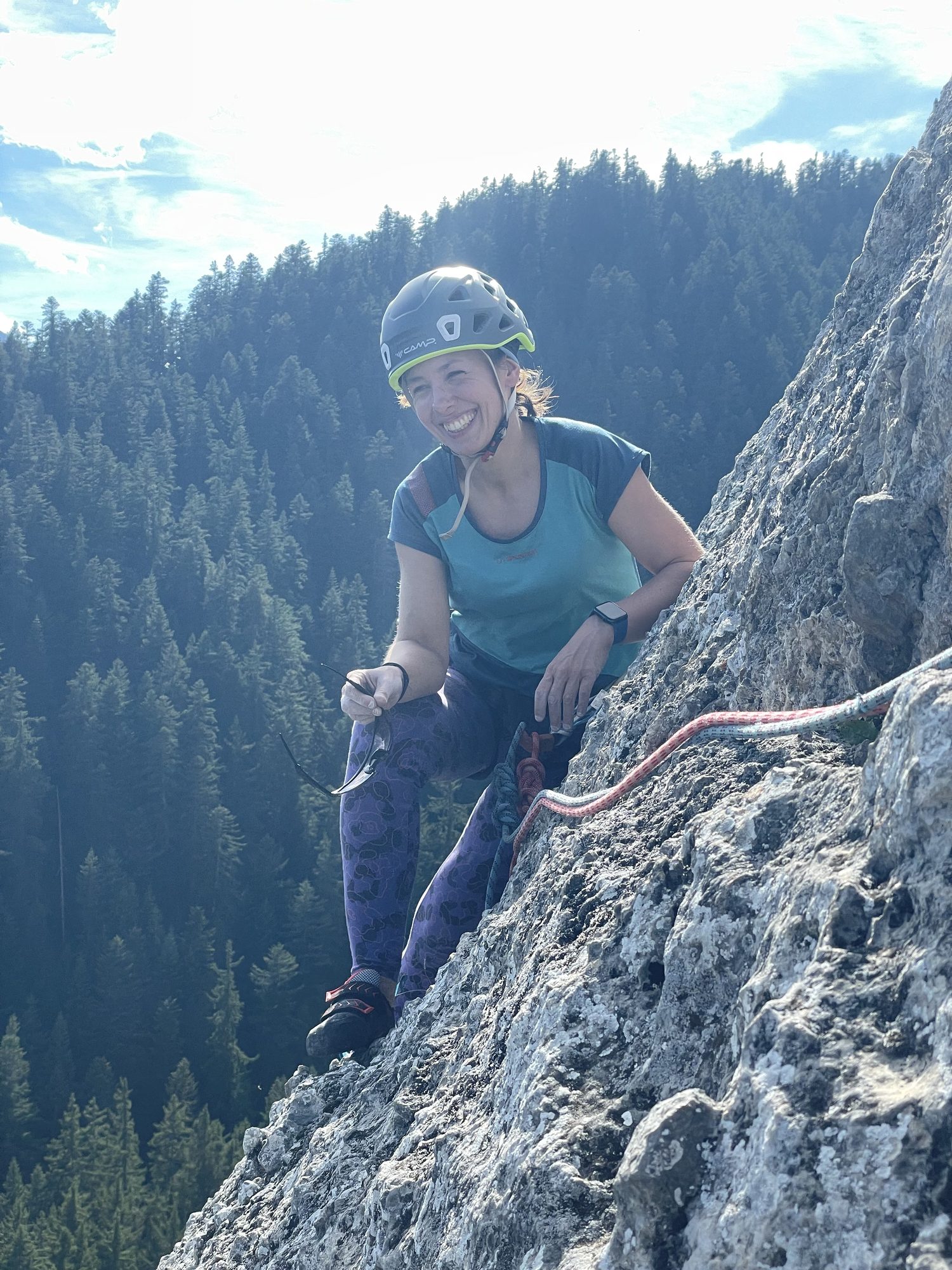 Grimpeuse souriante au relais, vallée en arrière-plan