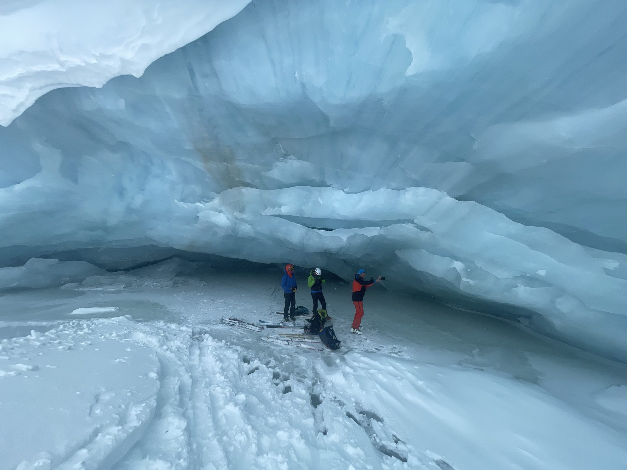 Groupe skieurs sous une arche de glace, au fond d'une crevasse glaciaire