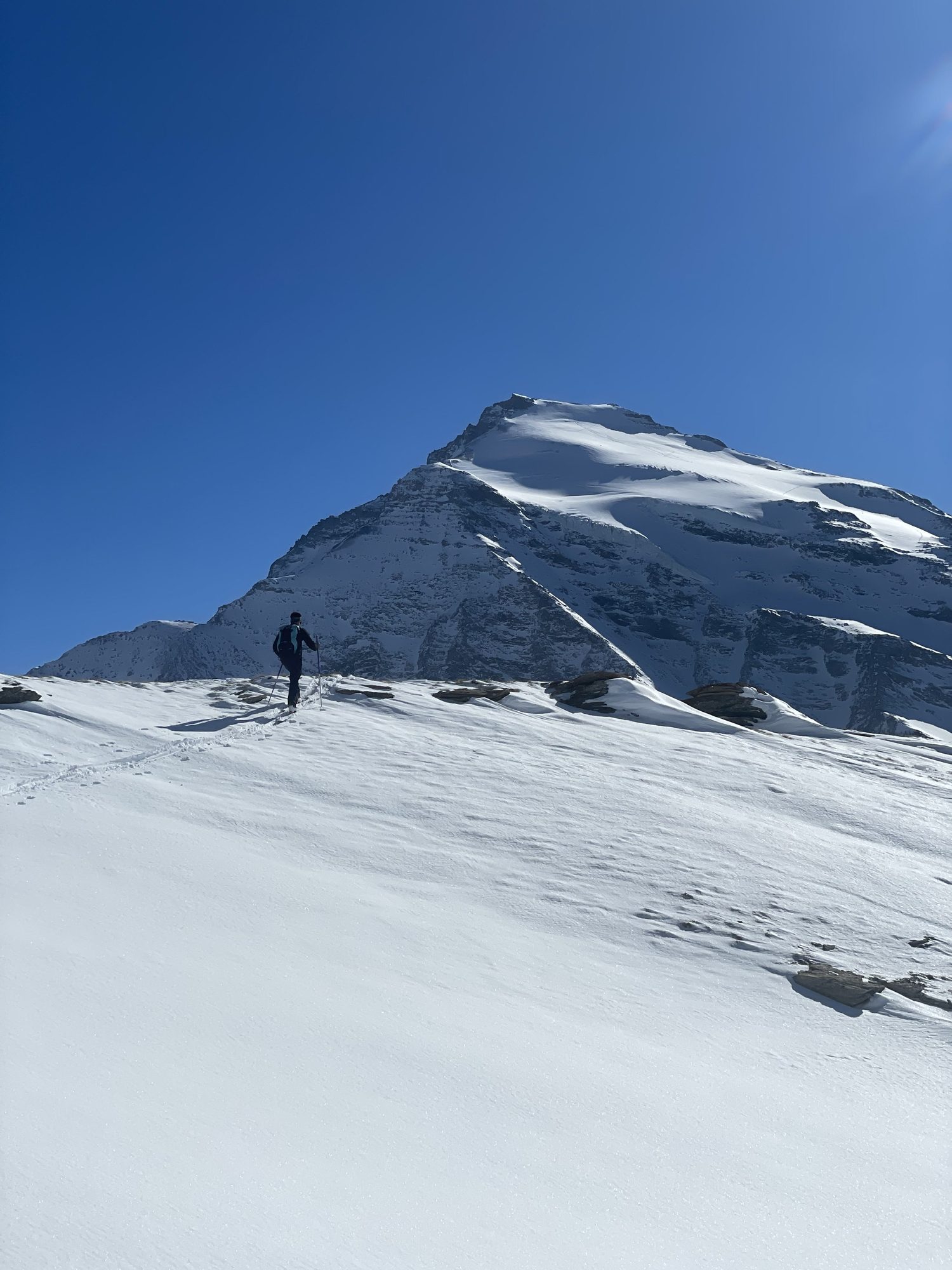 Skieur solitaire face à un sommet baigné de lumière