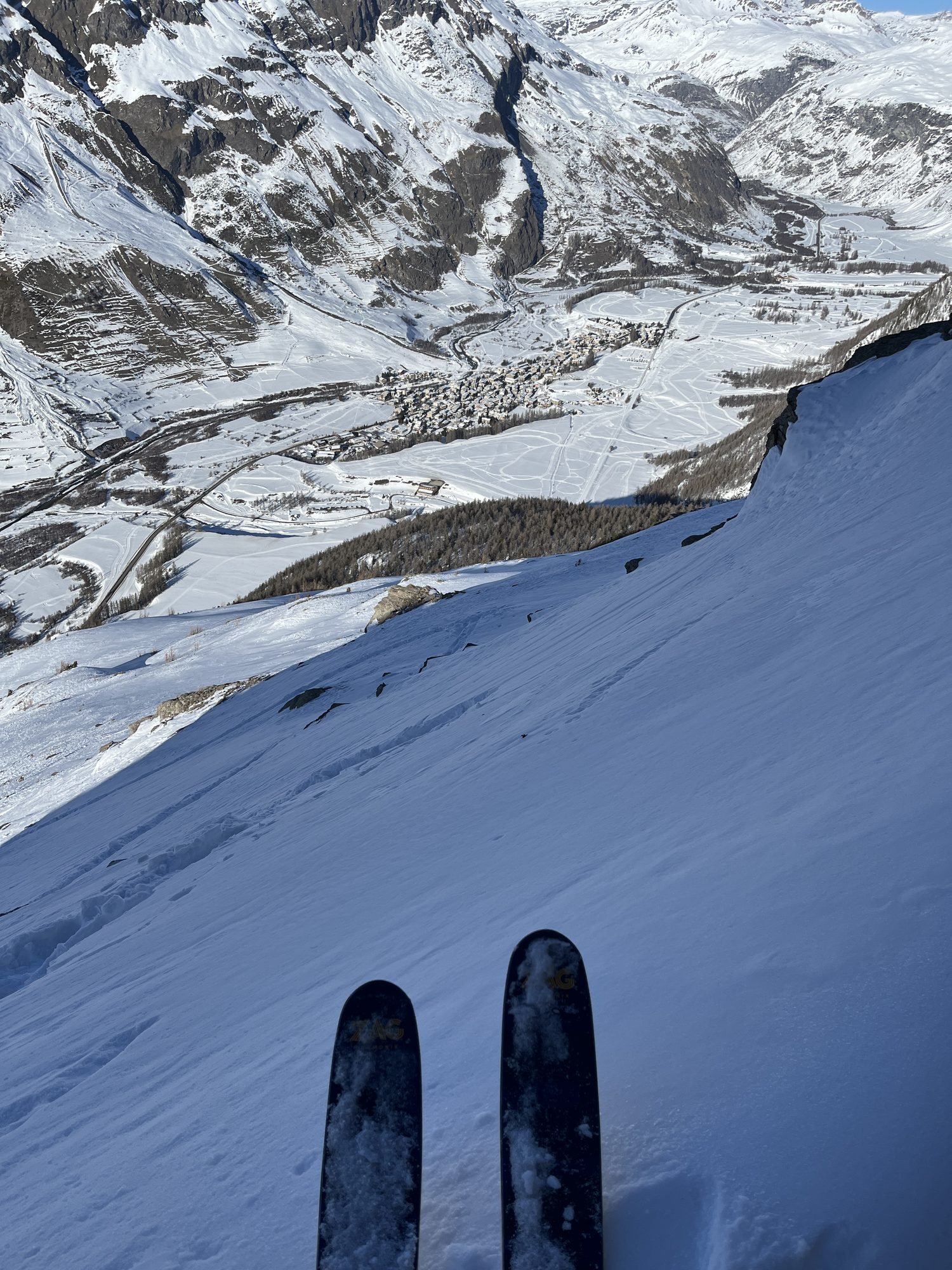 Skis aux pieds au sommet de la pente, le village en contrebas